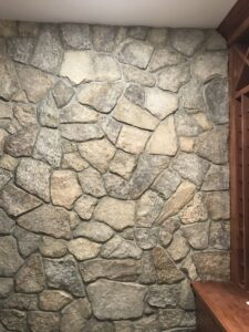 Interior accent wall constructed with irregular natural fieldstones in varied gray and brown tones, showcasing a rustic texture and visible mortar joints.